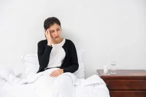 The sick woman had a migraine headache and the hands touched her head on