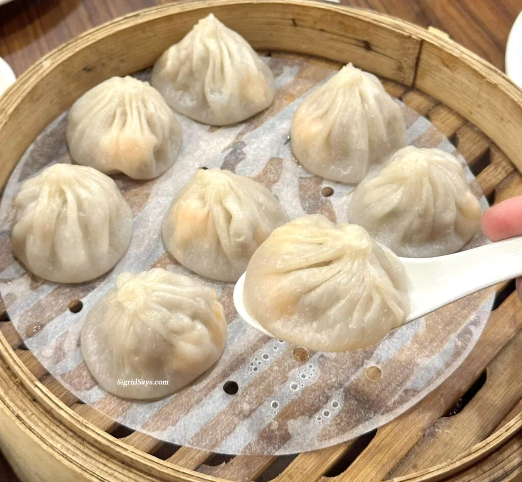 Xiao long bao in a steamer at Lantien Chinese Restaurant. One xiao long bao dumpling is in a soup spoon.