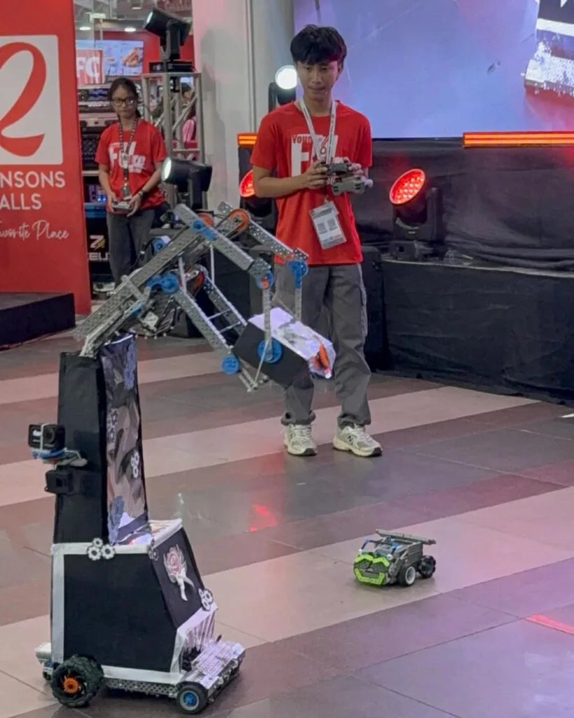 A Grade 11 student ushers the ribbon cutting ceremonies of the 18th Digital Expo with his remote-controlled robot.
